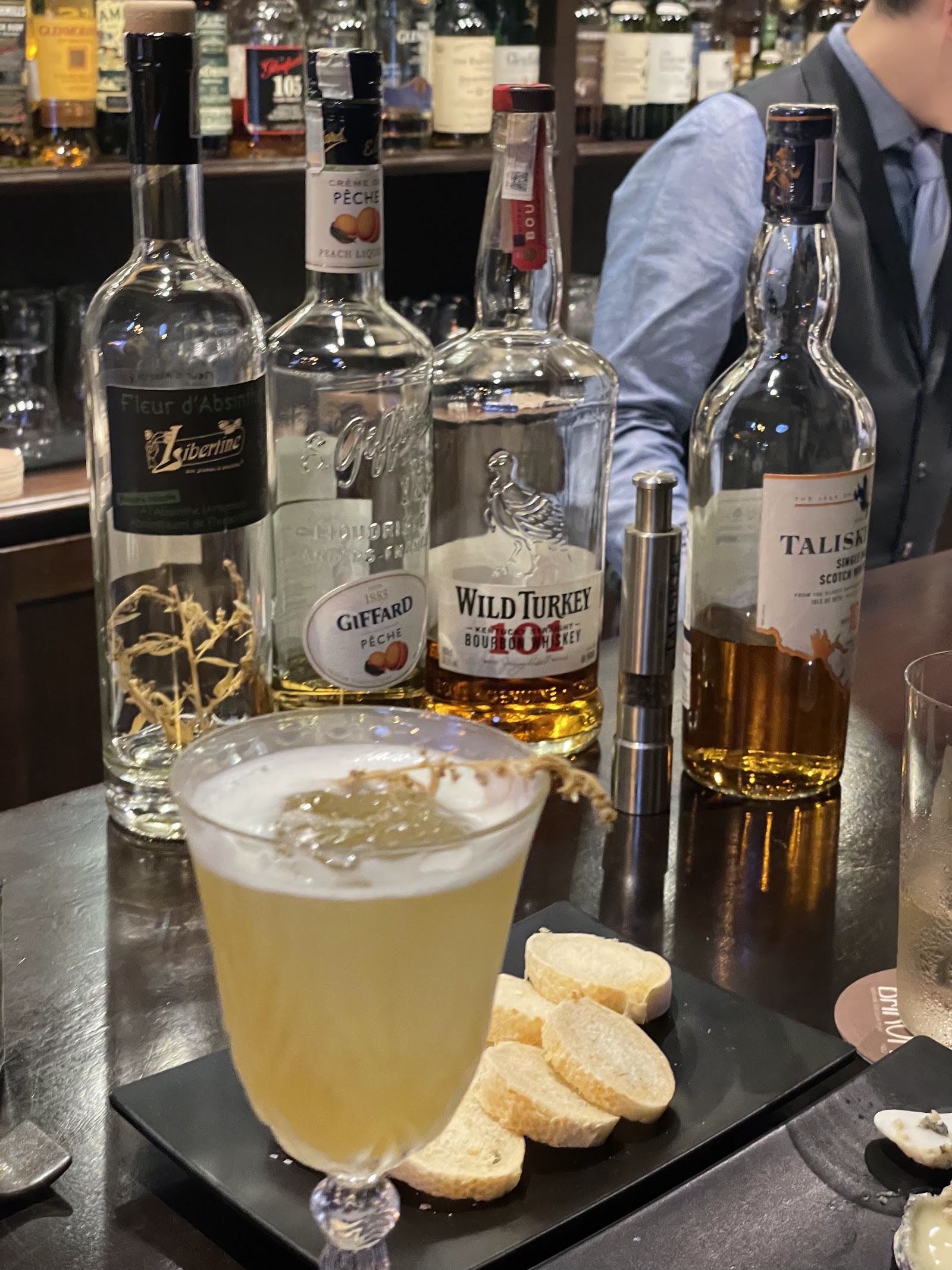 Một ly cocktail và những chai rượu tại Baron Bar