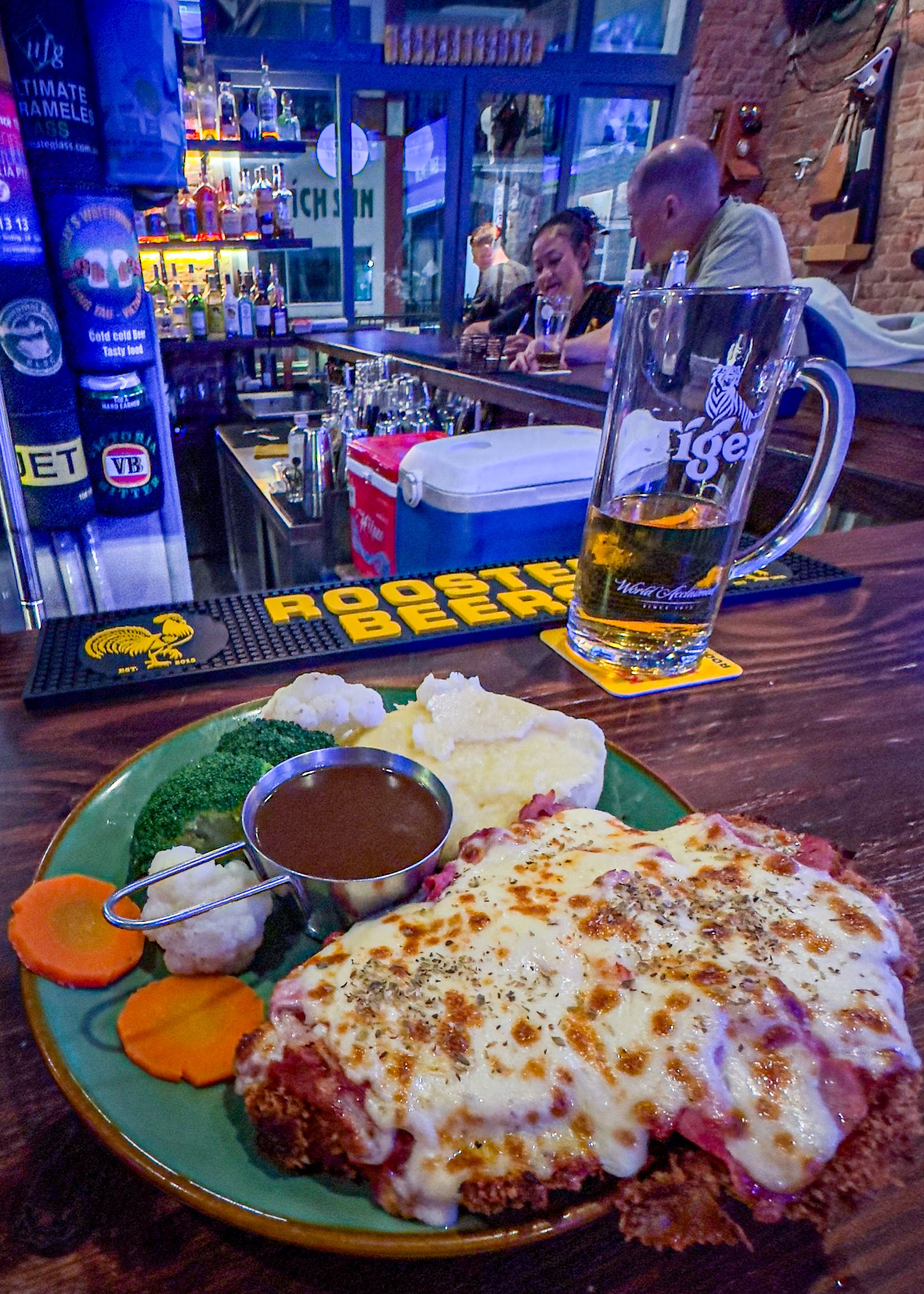 Chicken parma with mash, veg and gravy at the bar, the taps behind