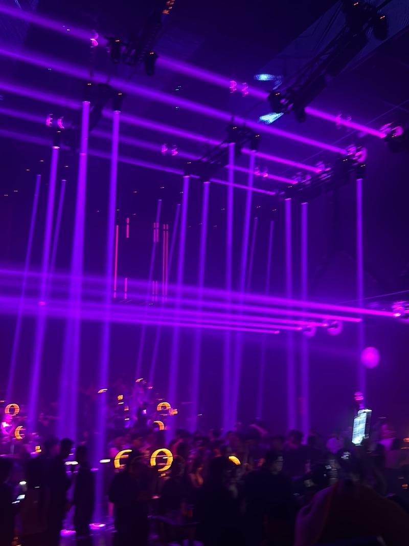 Inside APLUS Saigon, tables at the floor's edge under violet light
