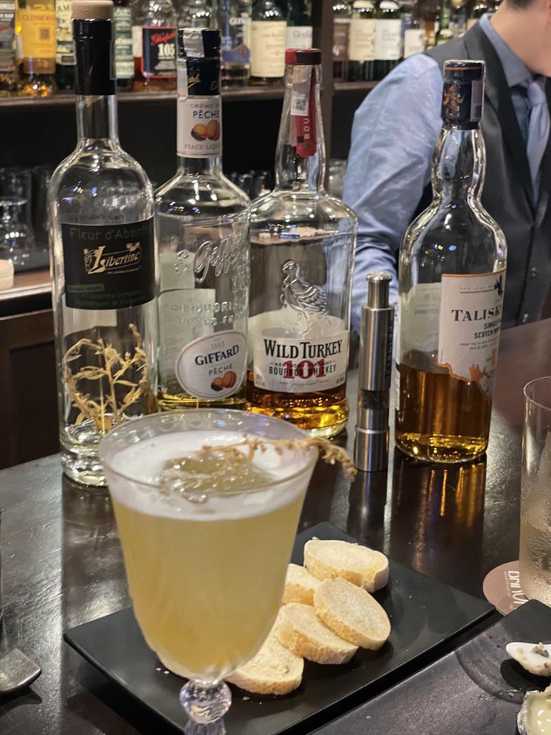 Một ly cocktail và những chai rượu tại Baron Bar