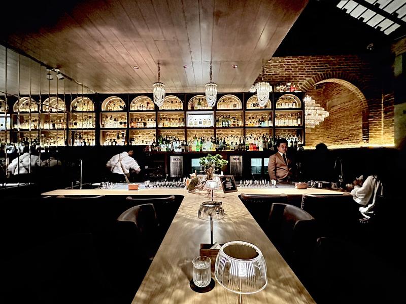 Quầy bar chính của The Enigma Mansion — mặt bàn đá và ánh đèn ấm
