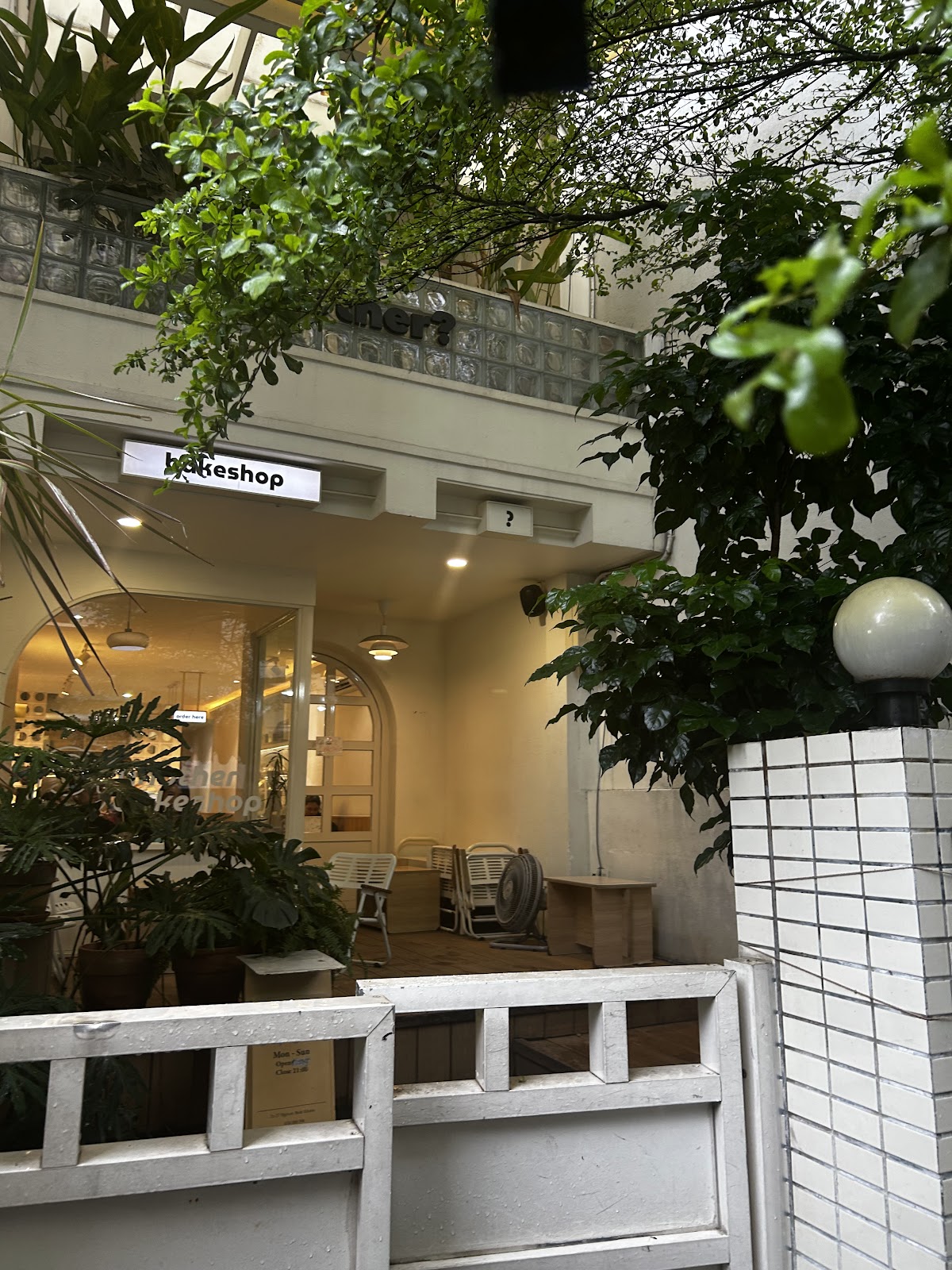 대문 너머 — 목재 데크 좌석, 식물, bakeshop 간판