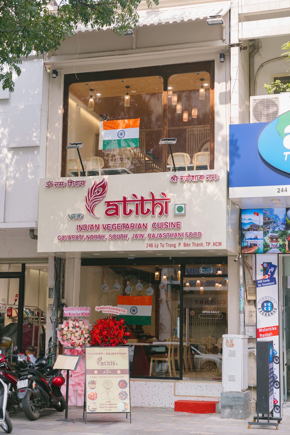 Daytime storefront — red atithi signboard, flags upstairs