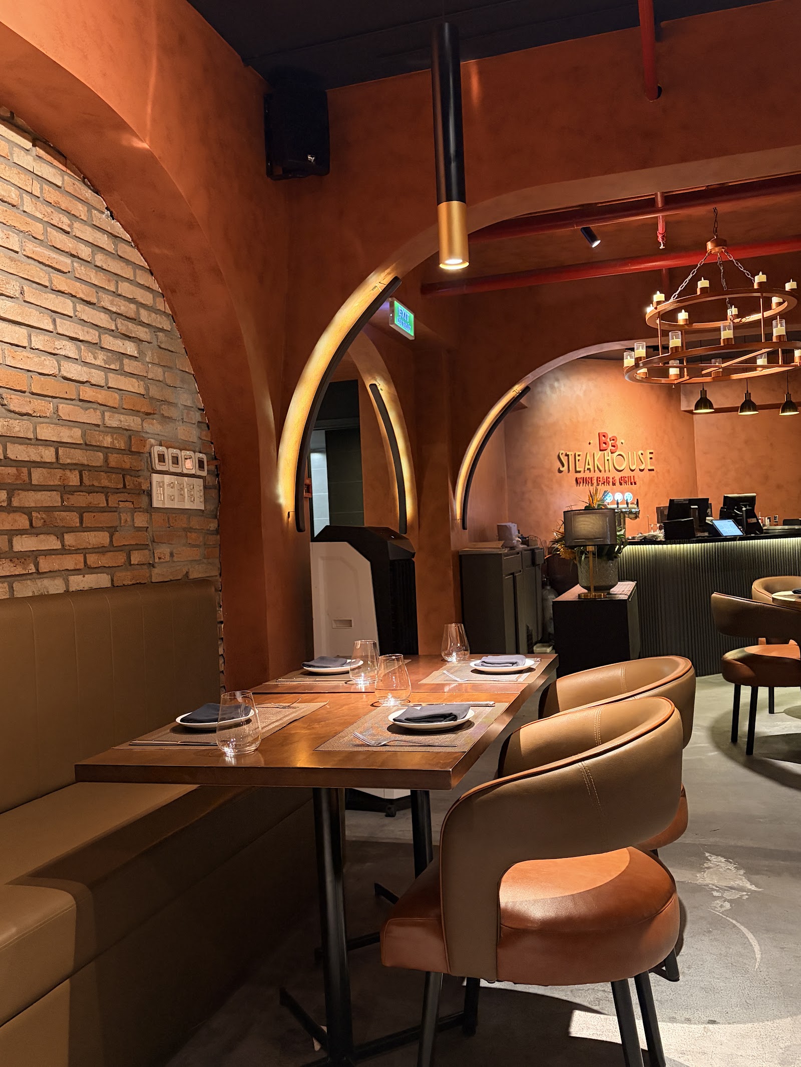 테라코타 벽의 B3 STEAKHOUSE WINE BAR & GRILL 간판, 세팅된 테이블