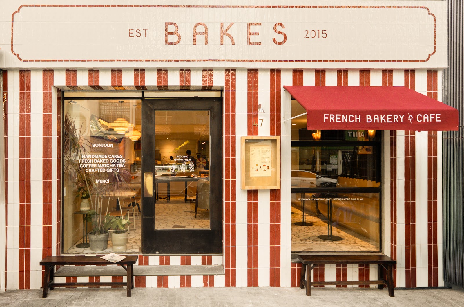 빨간색과 흰색 줄무늬 타일 파사드 — EST BAKES 2015 간판, 빨간 어닝, 나무 벤치