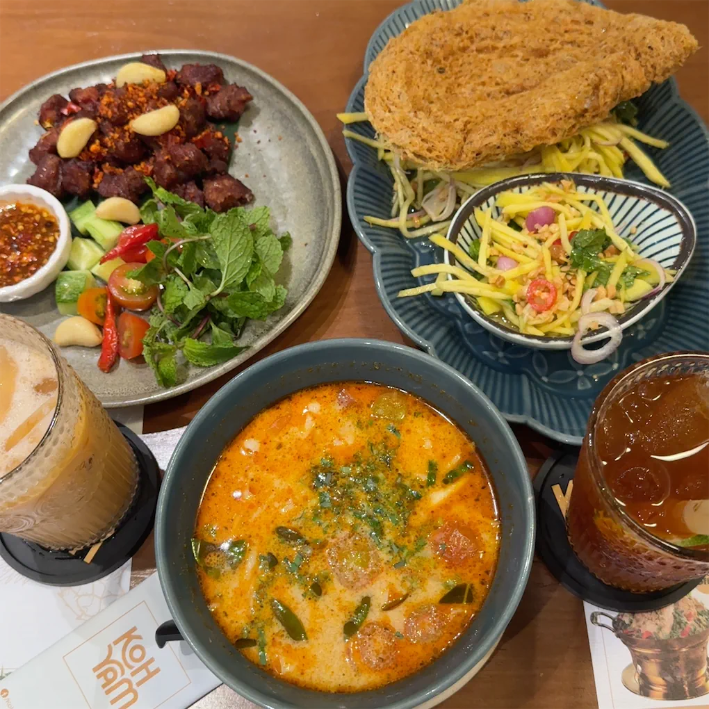 Bàn ăn chung — mì Tom Yum, bò nướng tỏi, gỏi xoài, trà sữa Thái đá