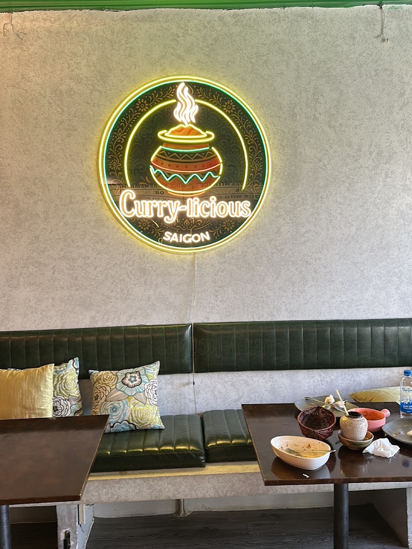 Neon Curry-licious SAIGON logo above the green banquette