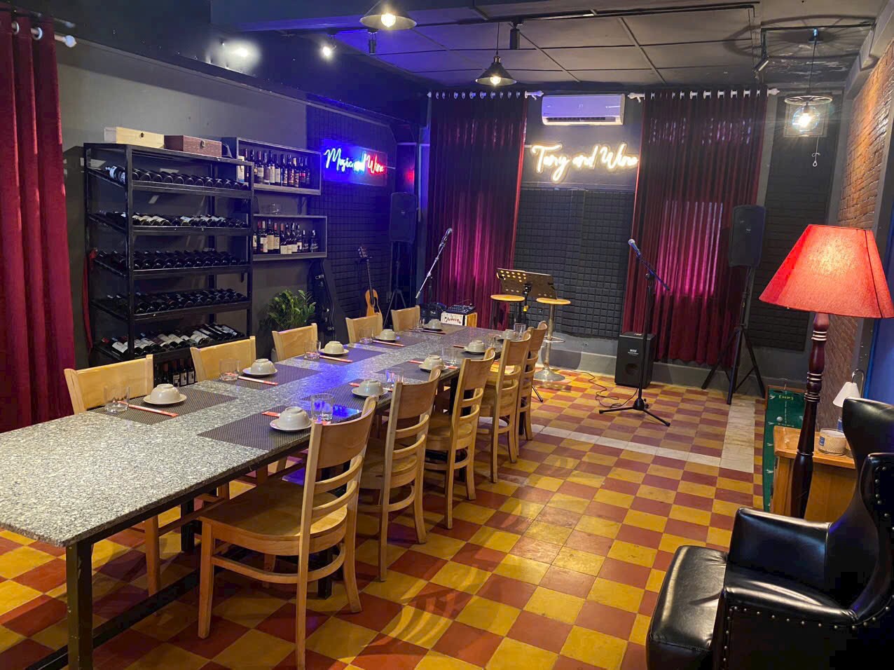 Upstairs private room with a long banquet table, wine rack and neon-lit stage