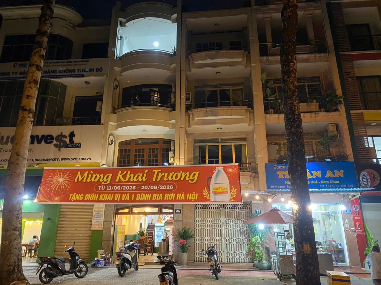 Exterior at night with a grand-opening banner and motorbikes