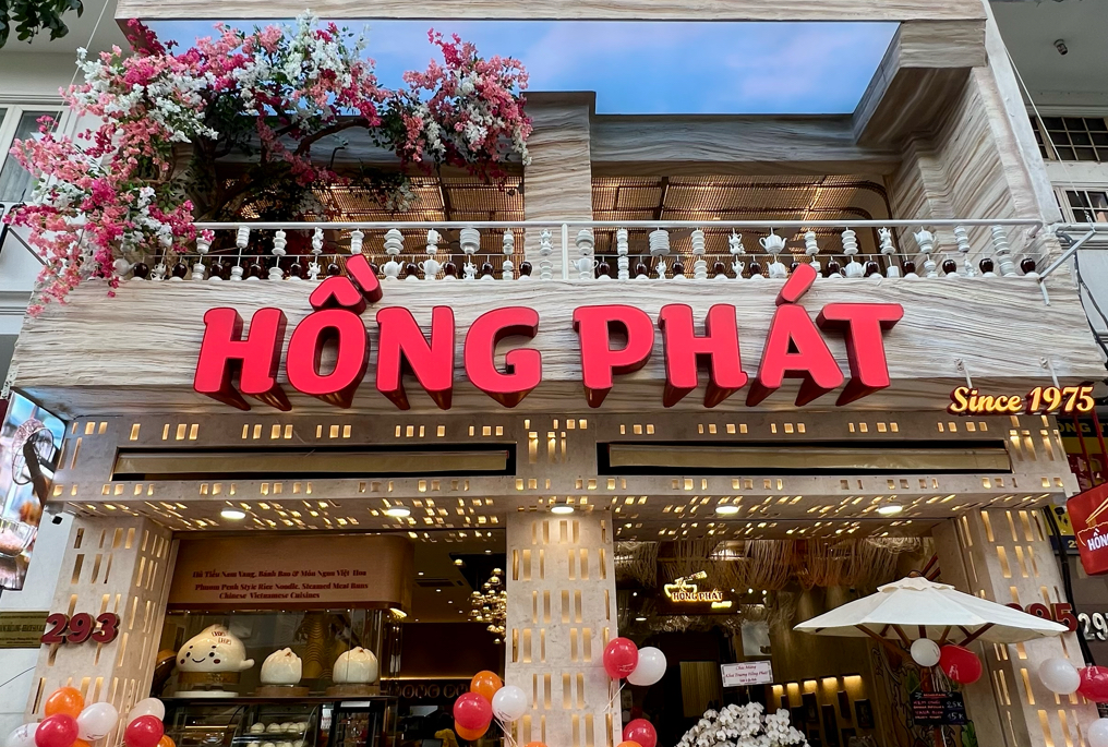 Storefront — red 3D HỒNG PHÁT letters, Since 1975, flowering tree, white balustrade