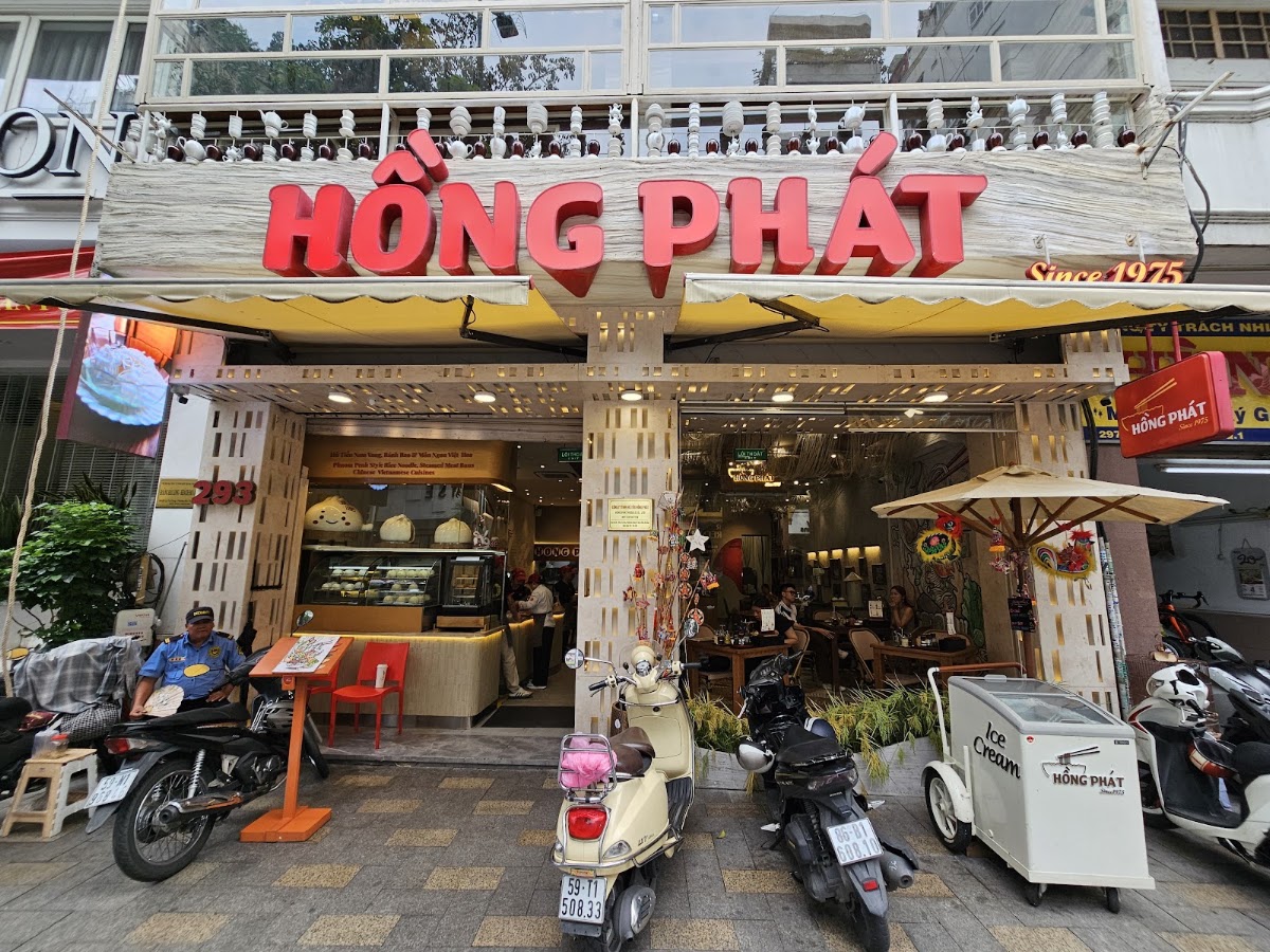 Street level — motorbikes, HỒNG PHÁT ice-cream cart, patio umbrella