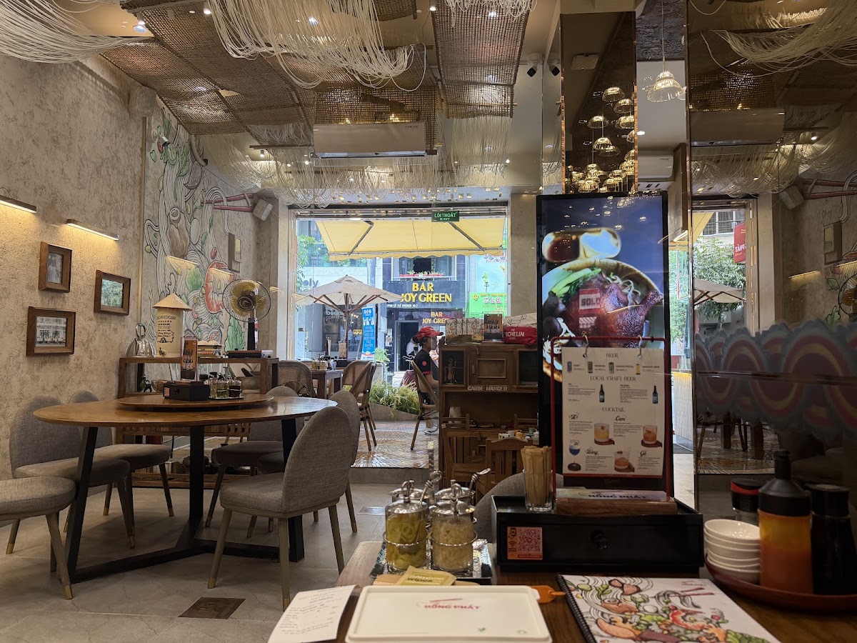 Dining room — round wooden tables, noodle mural, drinks board, street view