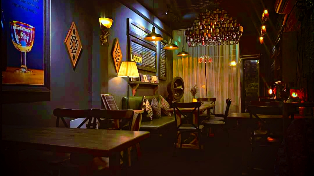 Wide dim lounge, Westvleteren poster, bottle chandelier