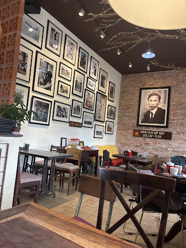 Gallery wall of black-and-white Hanoi photos, brick wall, Ho Chi Minh portrait and wooden sign