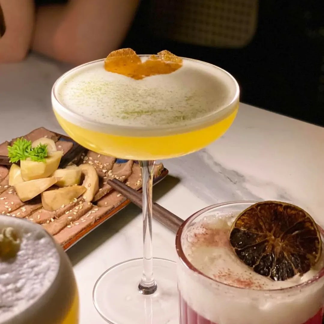 Yellow foam-capped coupe with dehydrated orange, pink coupe with dehydrated lime wheel, beef plate behind