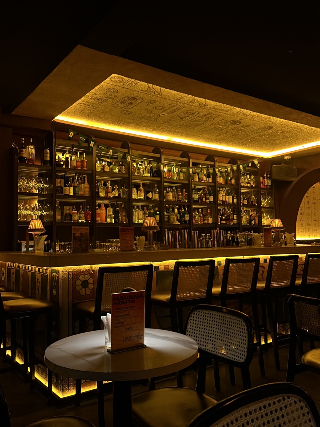 Full backlit bottle wall with HAVANA NIGHTS table tent on marble table