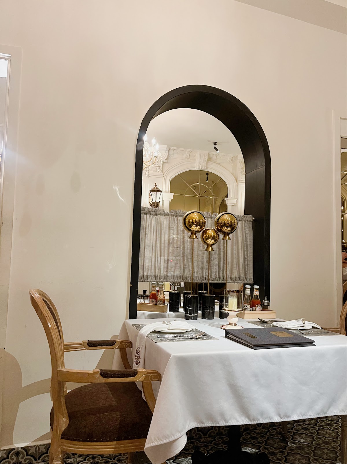 A set table with gold ornaments, framed by a tall black-trimmed arched doorway
