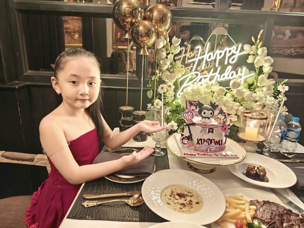 Celebration table dressing — neon Happy Birthday sign, white florals, gold balloons, candlelight