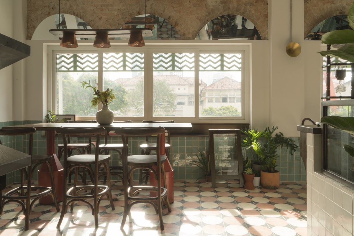 The main room — window wall, long communal table, copper cone pendants, brick arches with round mirrors