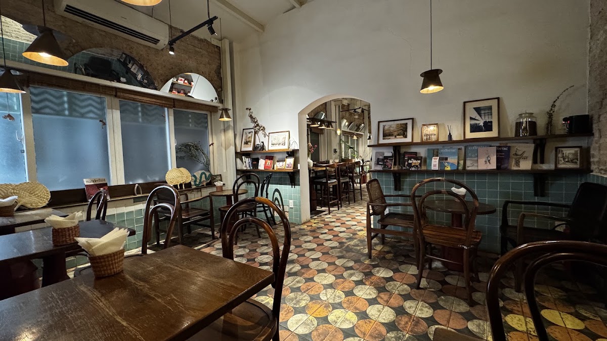 The main room in the evening — warm light, shelf wall with art and books, arch to the back room