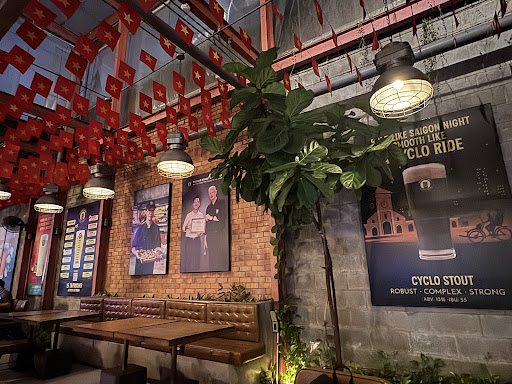 Tường gạch với poster Cyclo Stout, cờ dây, băng ghế da và bảng danh sách vòi bia