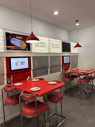 Solo-dining booths along the wall — white counter, curved privacy partitions, red stools