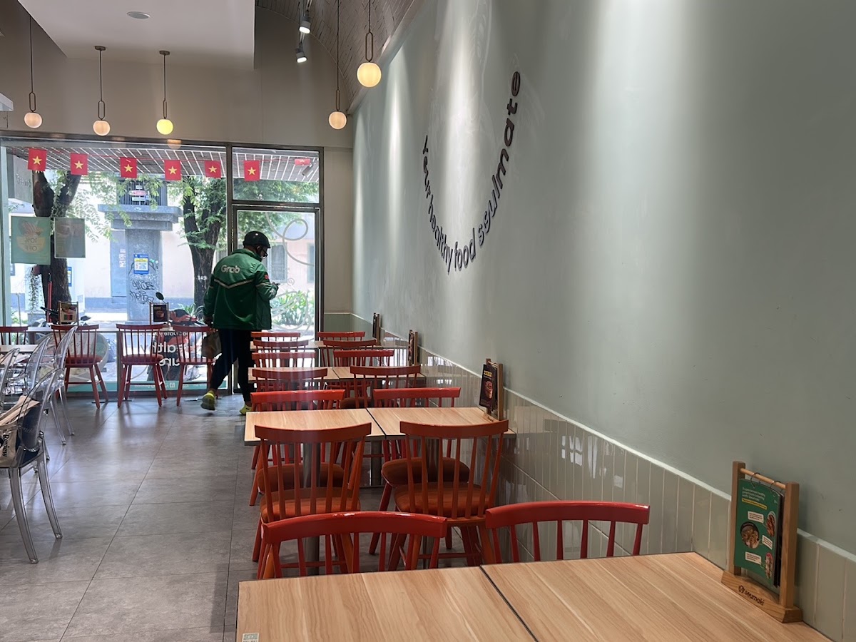 Hướng ra mặt kính — ghế cam, chữ cong “healthy food soulmate”, đèn tròn