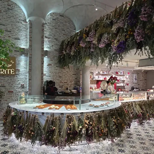 Circular display counter with dried-flower garlands, ceiling floral installation, brick columns, patterned floor