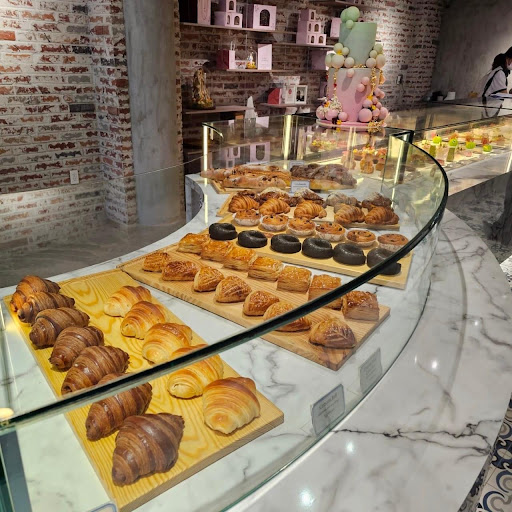 Curved marble/glass case: croissants, chocolate donuts, pastries on wooden boards