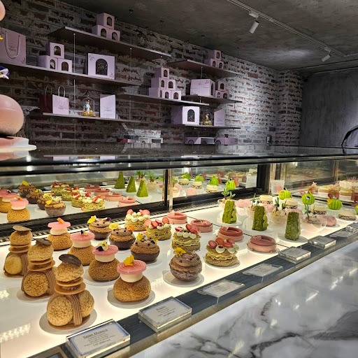 Wide case: choux pastries, mini cakes, green matcha trees, pink gift boxes on wooden shelves