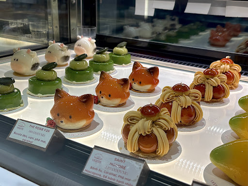 Signature shaped cakes close-up: ROSIE FOX fox cakes, pig faces, piped-cream SAINT HONORÉ with price labels